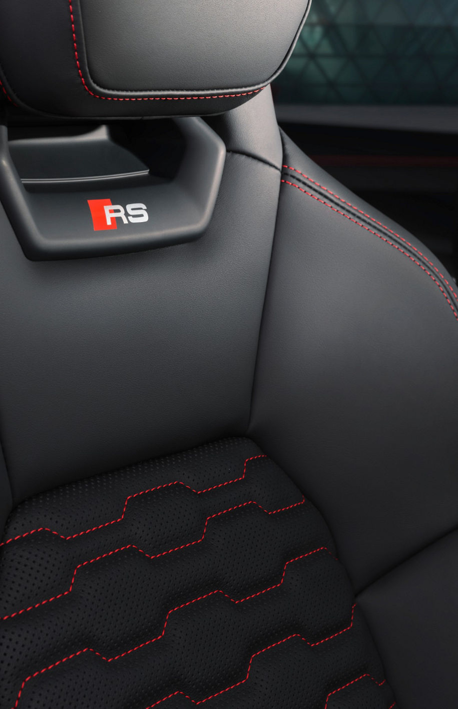 Close up of an Audi car seat, featuring the RS logo and red stiches